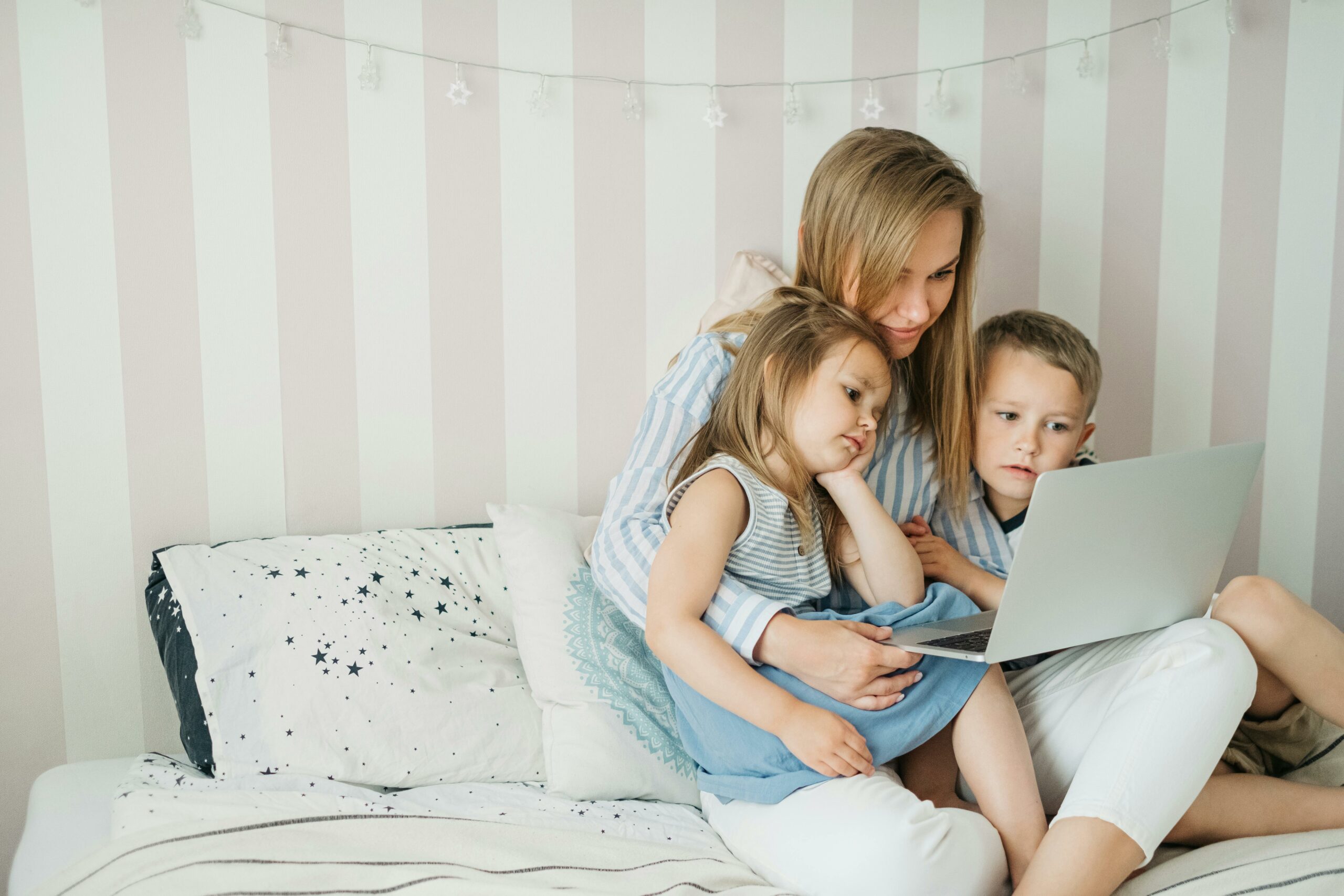 Mother and children bonding over a laptop at home, creating joyful family moments.